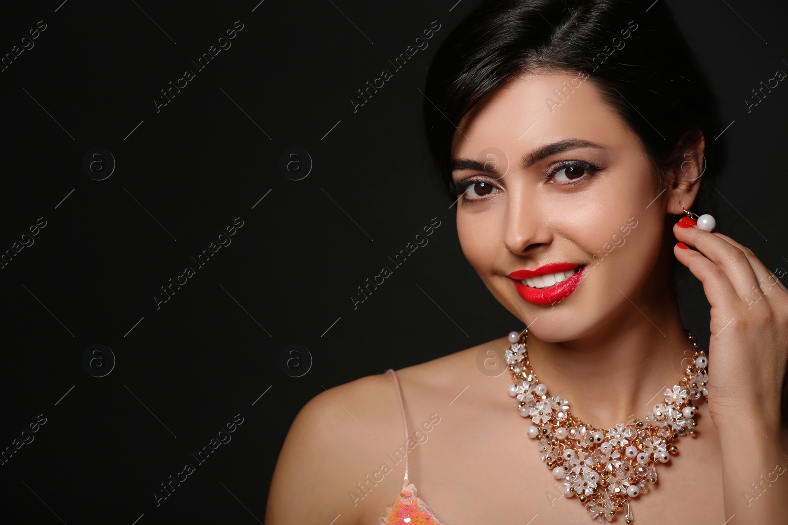 Photo of Beautiful young woman with elegant jewelry on dark background. Space for text