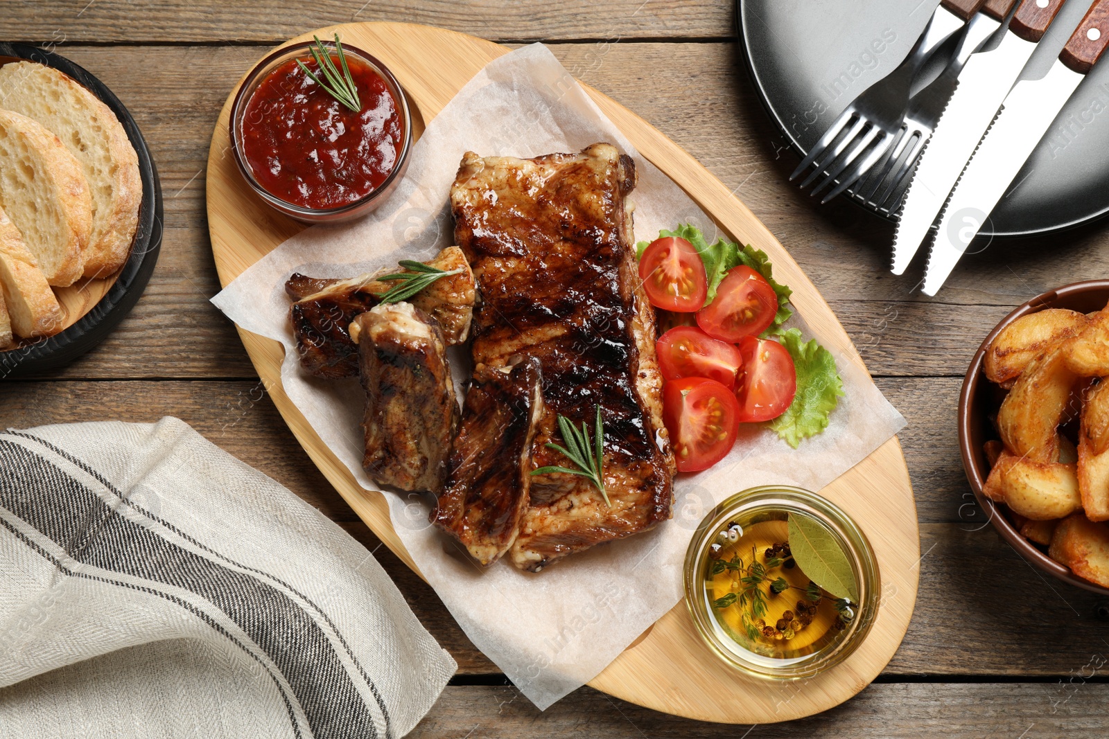 Photo of Delicious grilled ribs served on wooden table, flat lay