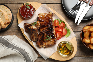 Delicious grilled ribs served on wooden table, flat lay