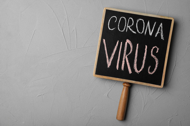 Photo of Chalkboard with phrase CORONA VIRUS on light grey background, top view. Space for text
