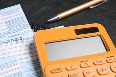 Photo of Calculator, documents and pen on black table, closeup. Tax accounting