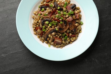 Delicious lentils with mushrooms, bacon and green onion on grey textured table, top view