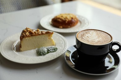 Cup of fresh coffee and desserts on white table