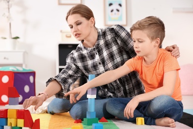 Young woman and little boy with autistic disorder playing at home