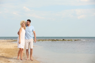 Happy romantic couple walking on beach, space for text