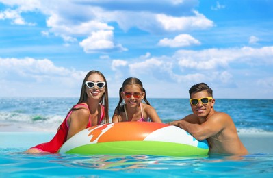 Image of Happy family in outdoor swimming pool near sea on sunny day