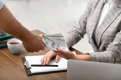 Man giving bribe money to woman at table, closeup