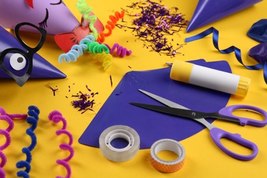Photo of Handmade party hats, template and tools on yellow background