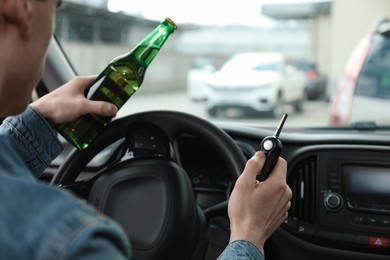 Man with bottle of beer driving car, closeup. Don't drink and drive concept