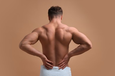 Photo of Man suffering from back pain on beige background, back view