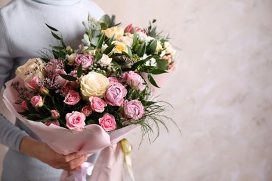 Photo of Woman with bouquets of beautiful flowers on beige background, closeup. Space for text