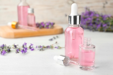 Photo of Bottles with natural lavender essential oil on white wooden table. Space for text