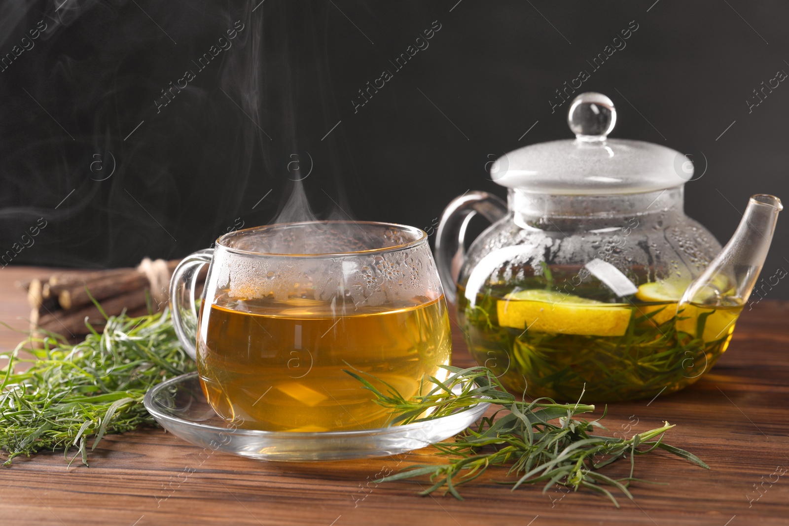 Photo of Homemade herbal tea and fresh tarragon leaves on wooden table