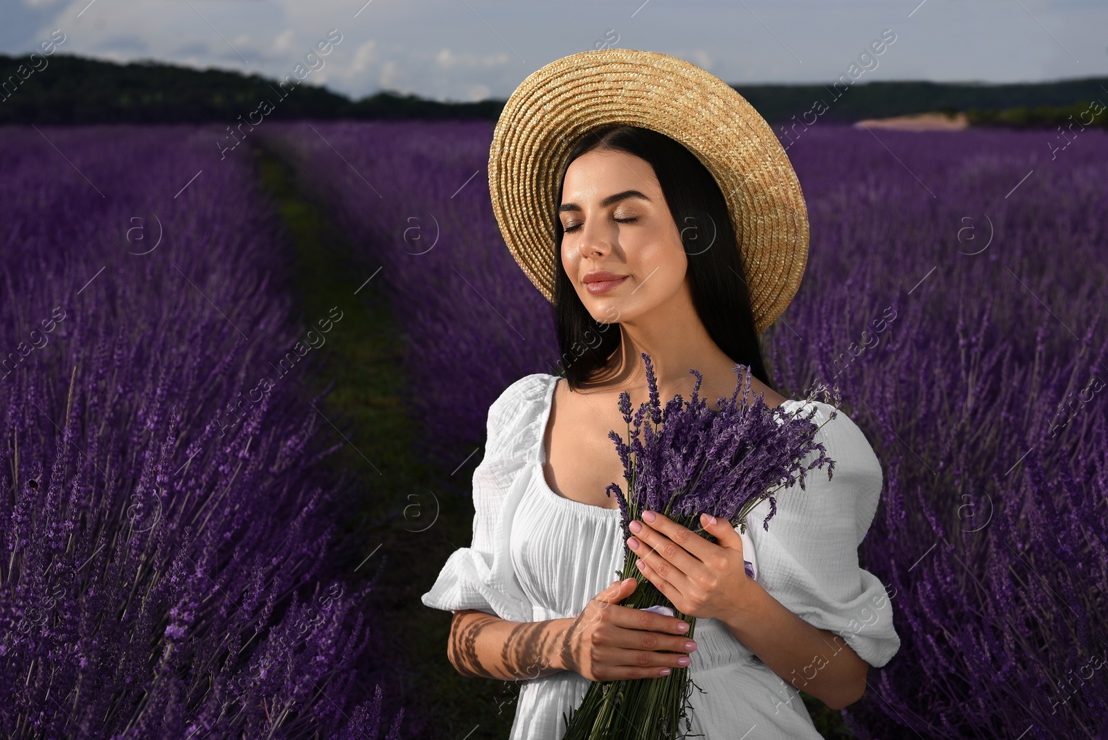 Photo of Beautiful young woman with bouquet in lavender field