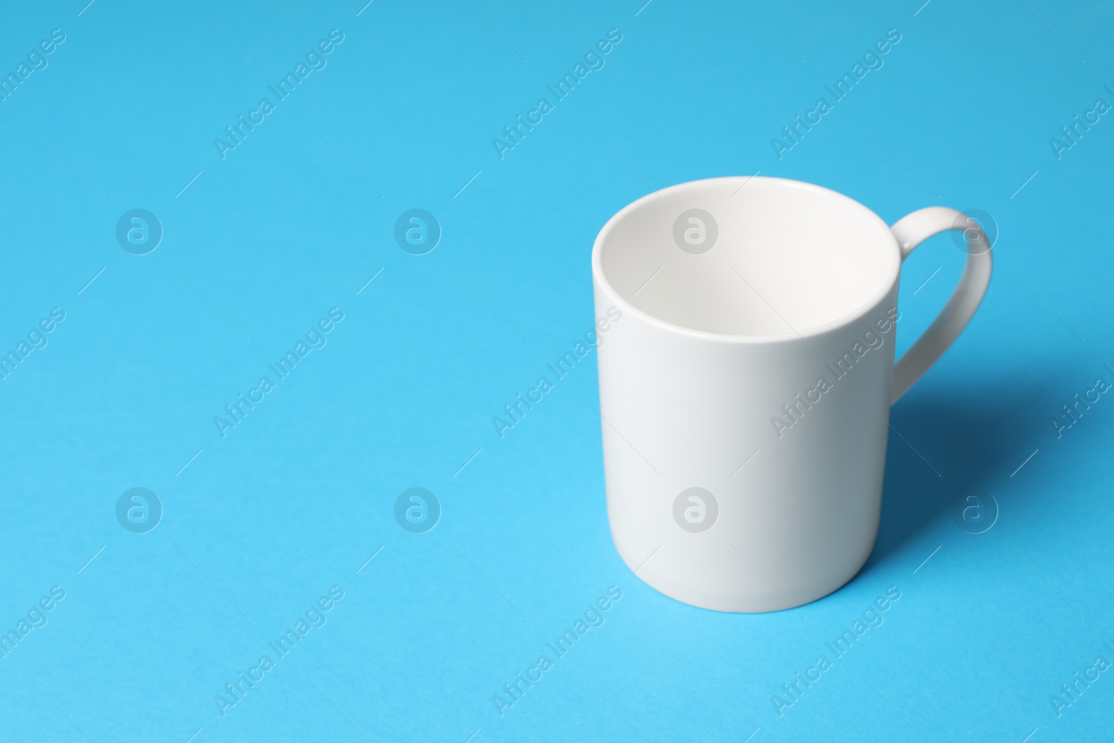One white ceramic mug on light blue background, space for text Photo of One white ceramic mug on light blue background, space for text