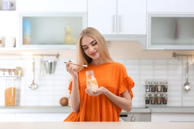 Photo of Young woman with yogurt in kitchen