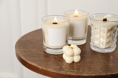 Photo of Different soy candles on wooden table indoors