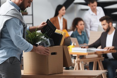 Photo of Young dismissed man packing stuff into box at office, closeup. Space for text