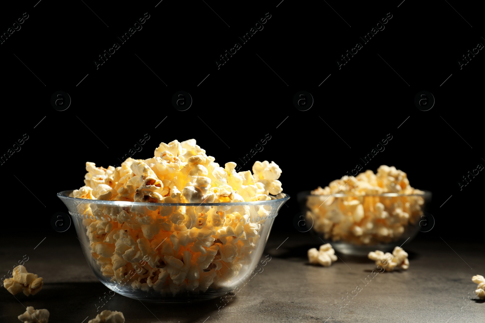 Photo of Tasty popcorn in bowl on table against black background. Space for text