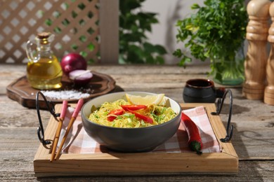 Photo of Stir-fry. Tasty noodles with vegetables and meat in bowl served on wooden table