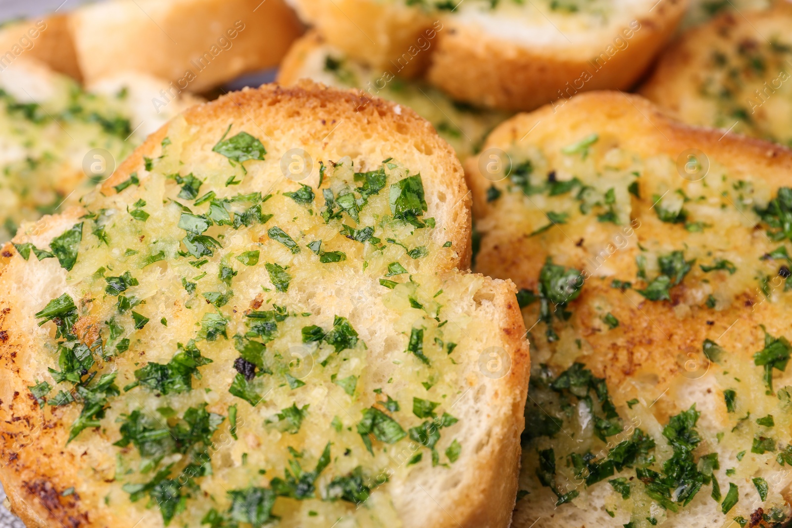 Photo of Slices of toasted bread with garlic and herbs as background, closeup