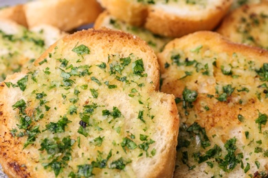 Photo of Slices of toasted bread with garlic and herbs as background, closeup