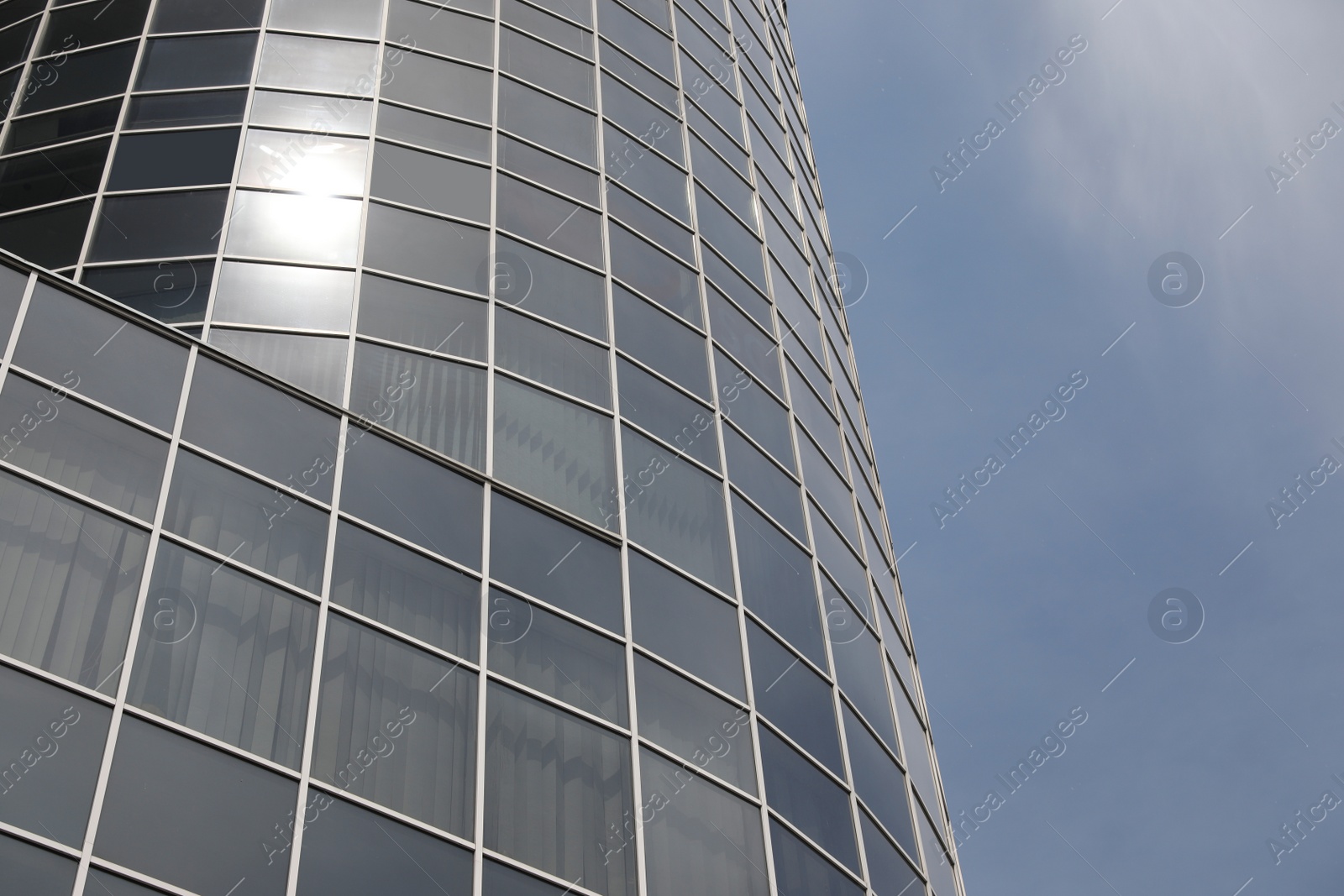 Photo of Modern building with tinted windows against sky, low angle view. Urban architecture