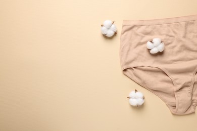 Photo of Comfortable women's underwear and cotton flowers on beige background, flat lay. Space for text