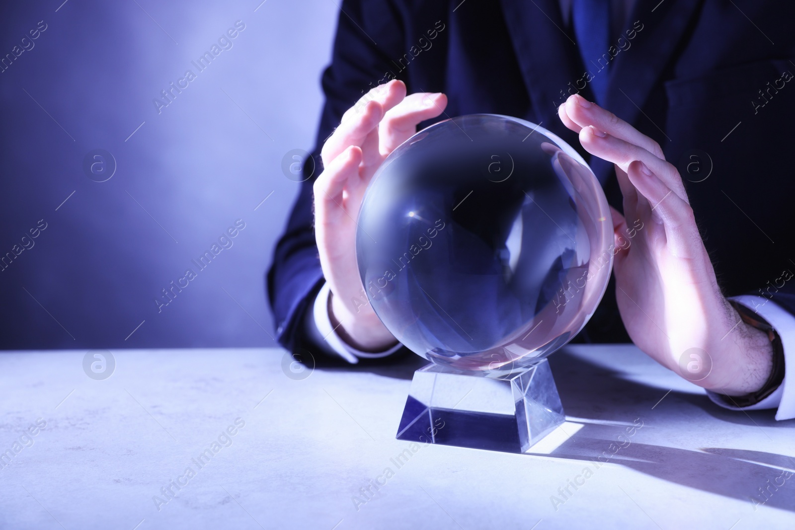 Photo of Businessman using crystal ball to predict future at table, closeup. Space for text