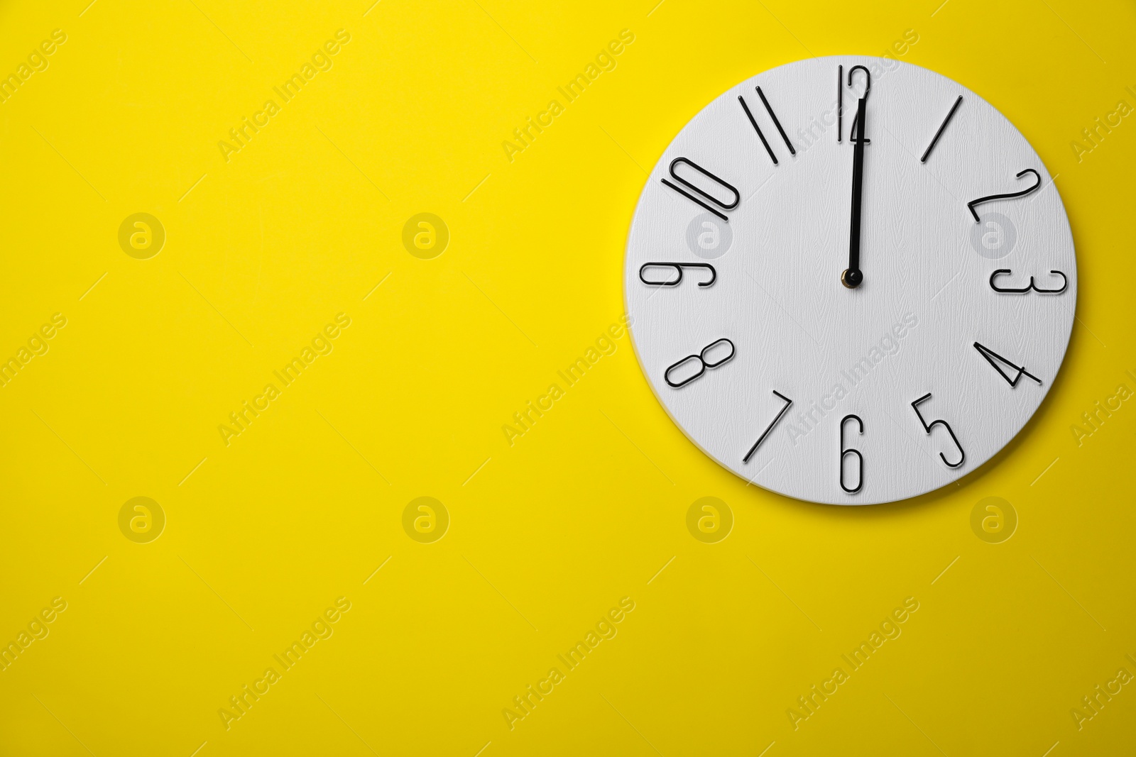 Photo of Modern clock on yellow background, top view. Space for text