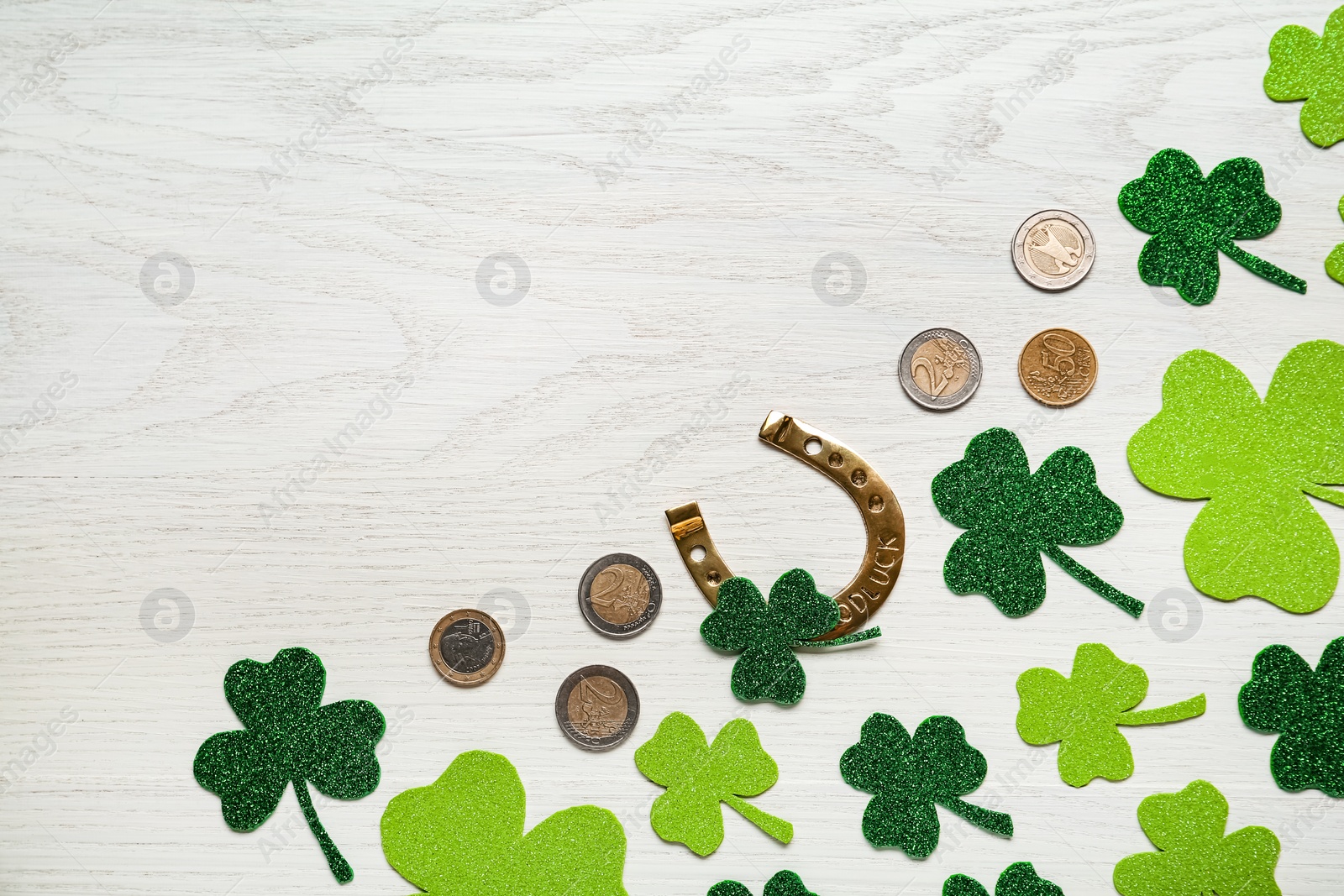 Photo of Flat lay composition with golden horseshoe on white wooden table, space for text. Saint Patrick's Day celebration