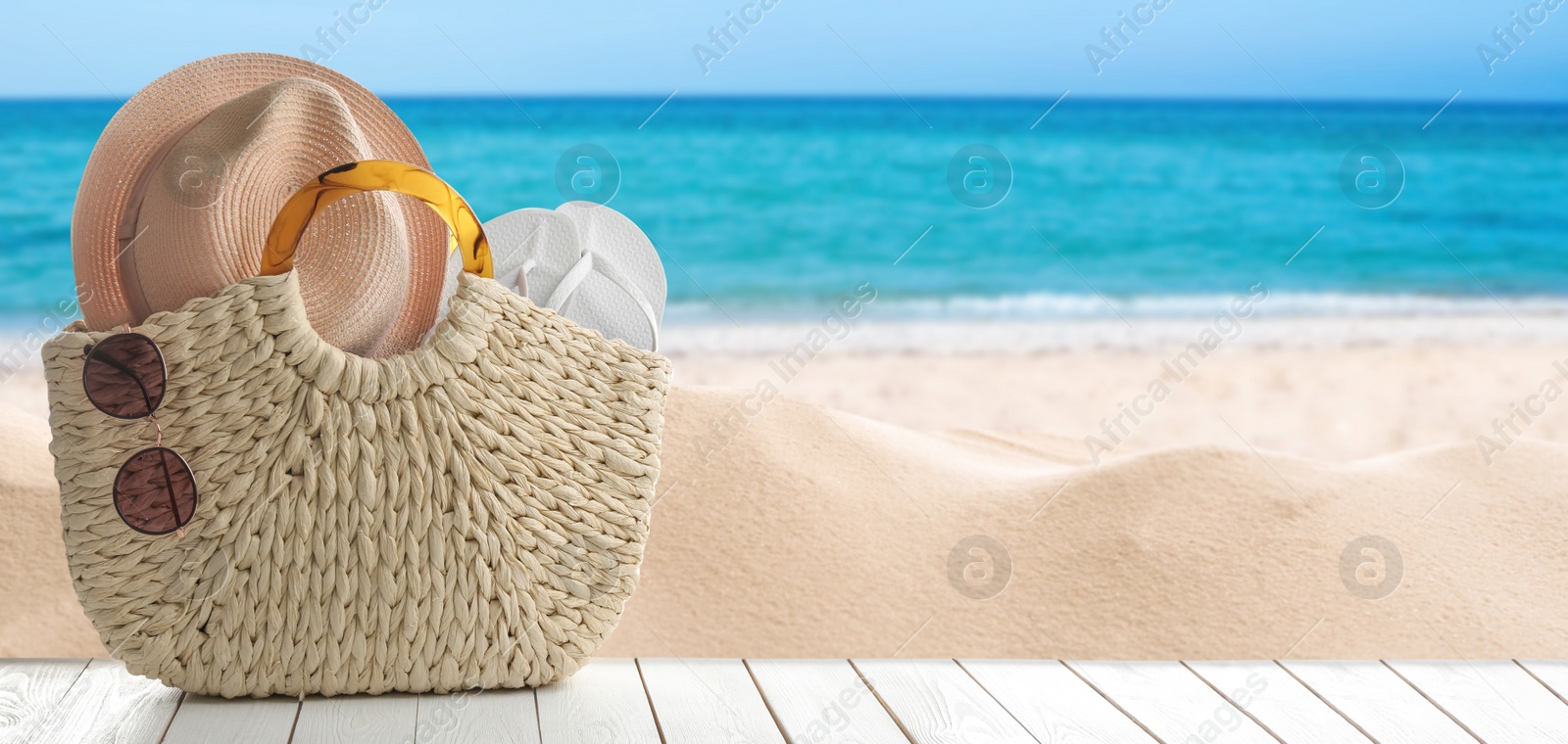 Image of Beach accessories on wooden surface near ocean, space for text. Banner design 