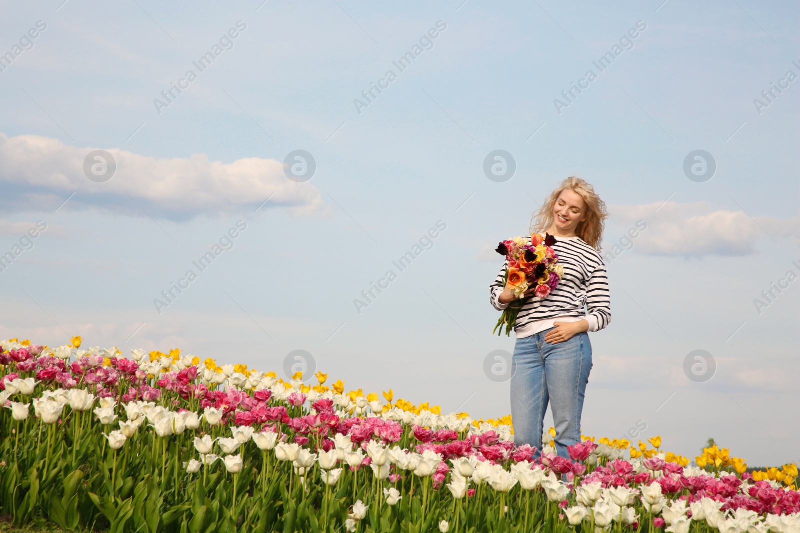 Photo of Happy woman with spring bouquet of flowers in beautiful tulip field on sunny day