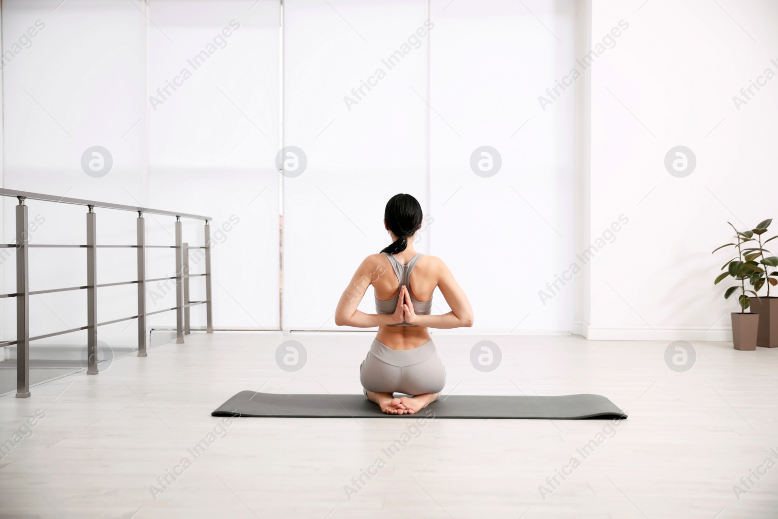 Photo of Young woman practicing seiza asana in yoga studio, back view. Vajrasana pose