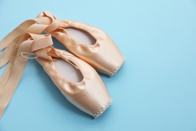 Photo of Ballet shoes. Elegant pointes on light blue background, space for text