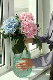 Woman with bouquet of beautiful hortensia flowers near window indoors, closeup