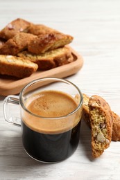 Photo of Tasty cantucci and cup of aromatic coffee on white wooden table. Traditional Italian almond biscuits