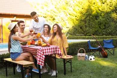 Photo of Happy friends with drinks having fun at barbecue party outdoors