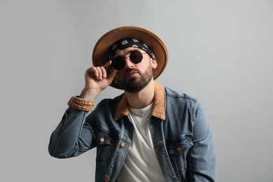 Photo of Fashionable young man in stylish outfit with bandana on grey background