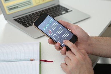 Man taking online test on smartphone at desk, closeup