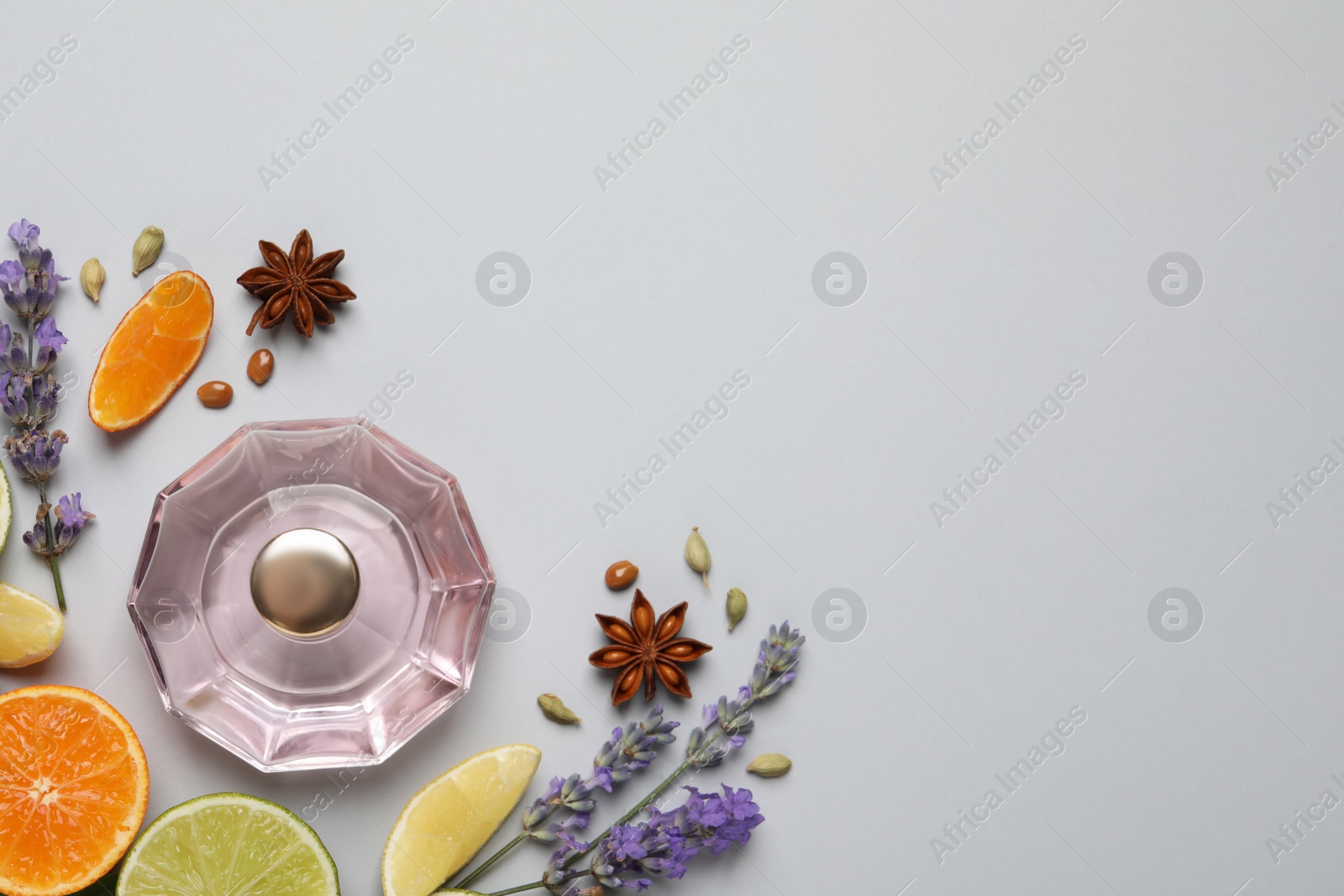 Photo of Flat lay composition with bottle of perfume, citrus fruits and flowers on light grey background. Space for text