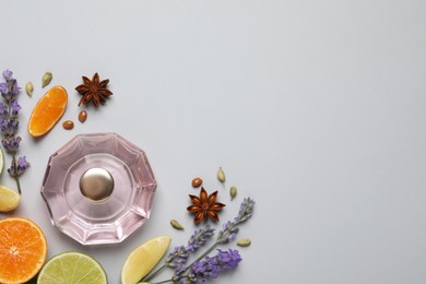 Photo of Flat lay composition with bottleperfume, citrus fruits and flowers on light grey background. Space for text