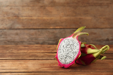 Delicious cut and whole dragon fruits (pitahaya) on wooden table. Space for text