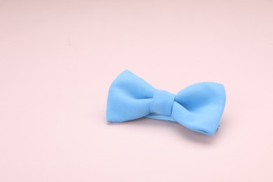 Photo of Stylish light blue bow tie on beige background. Space for text