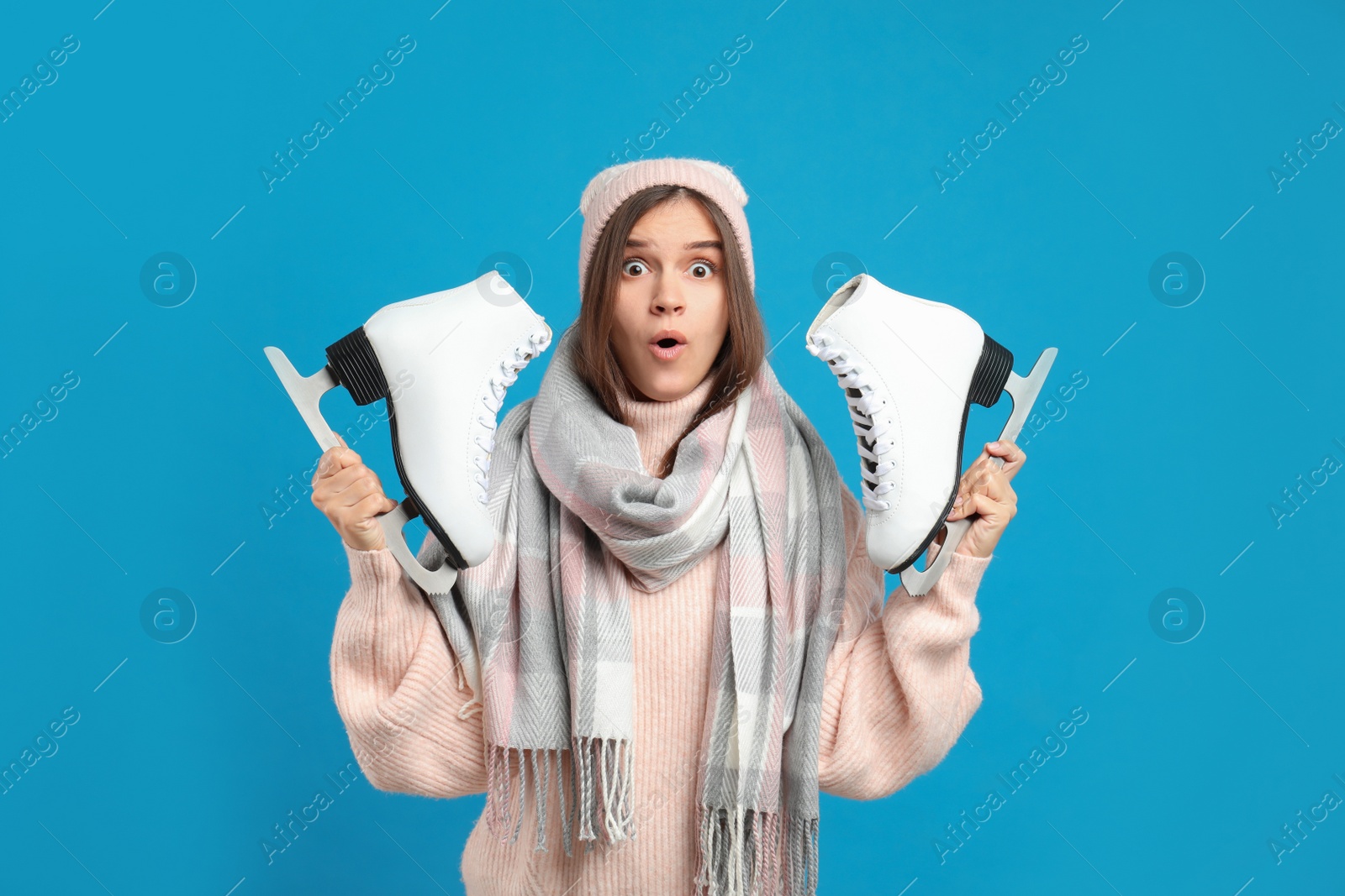 Photo of Emotional woman with ice skates on light blue background