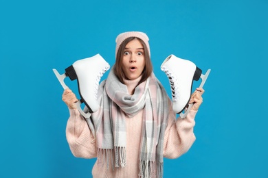 Photo of Emotional woman with ice skates on light blue background