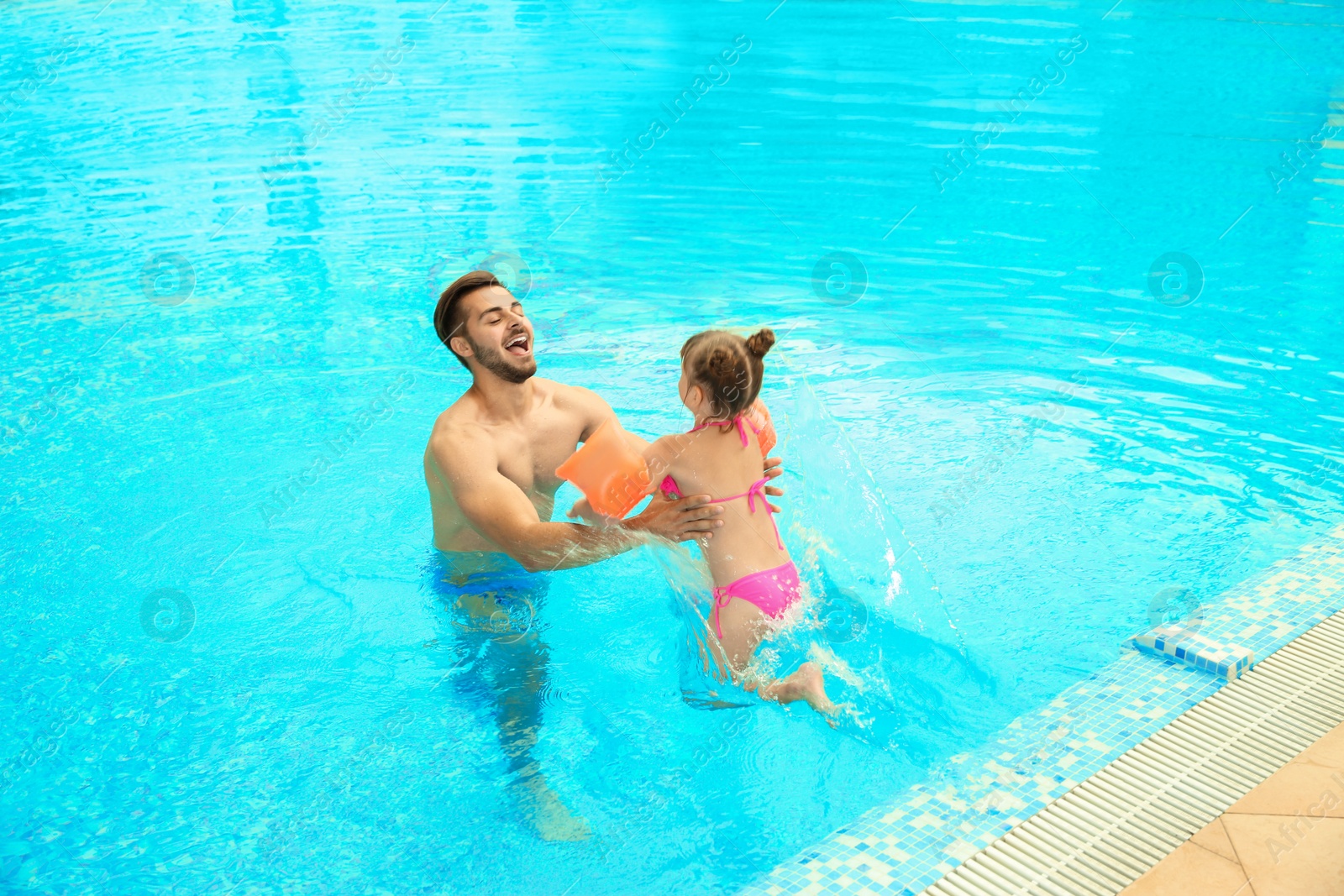 Photo of Father and daughter playing in swimming pool