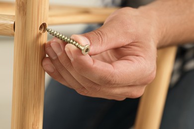 Photo of Man with self-tapping screw assembling furniture, closeup