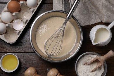 Photo of Flat lay composition with dough in bowl and metal whisk on wooden table