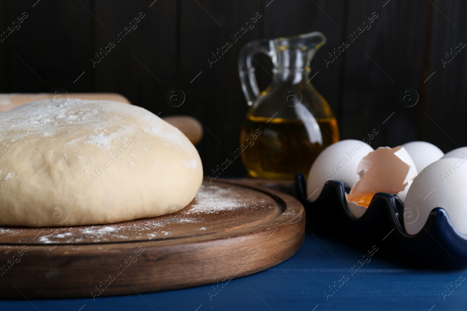 Photo of Fresh yeast dough and ingredients on blue wooden table, closeup